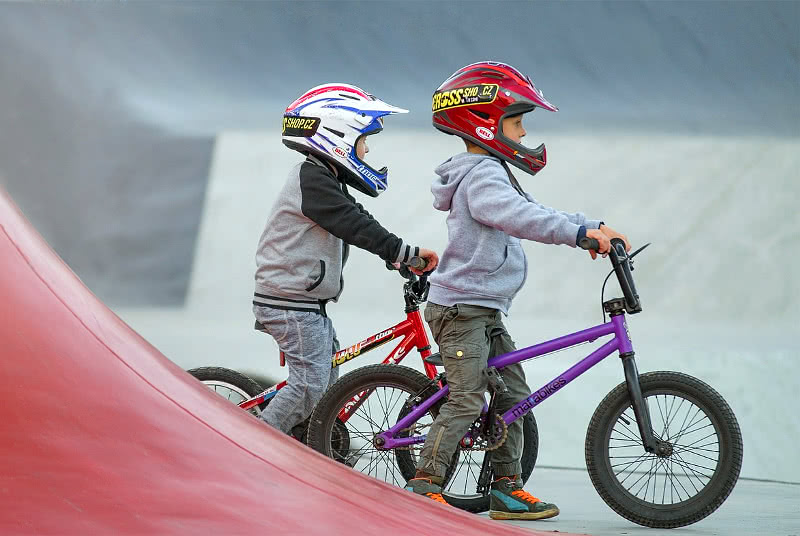Kaksi lasta BMX-pyörillä kypärä päässä